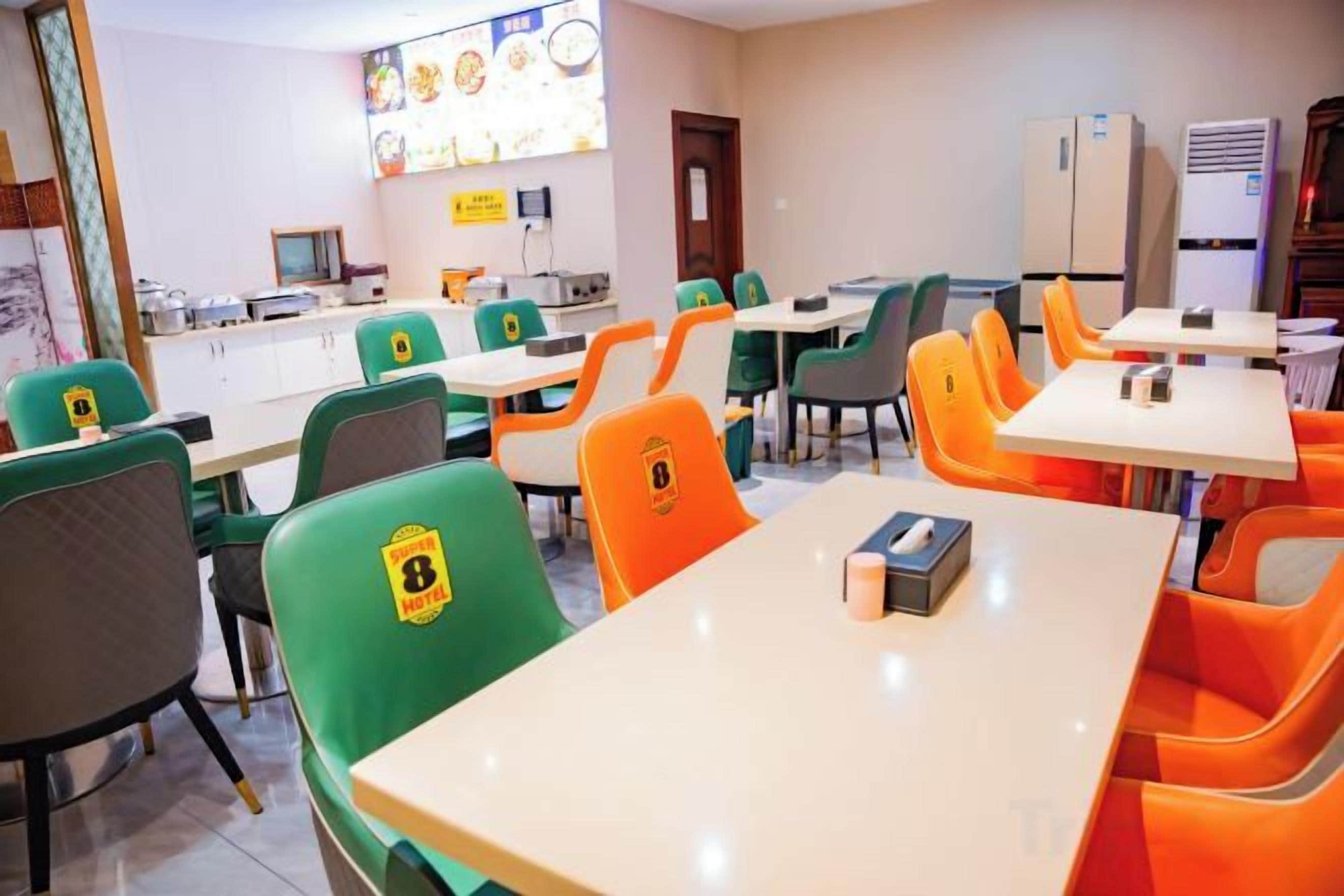 A dining area with tables and chairs, a kitchen counter, and a refrigerator.