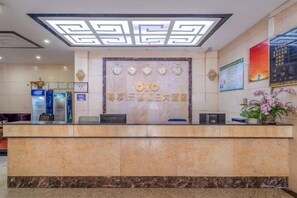 Een hotel receptie met een marmeren balie, een receptieplein en een klok aan de muur.