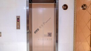 Een lift met een digitaal scherm waarop verdieping 8 staat, een QR-code en de tekst 'OYO Premium' op de binnenwand.