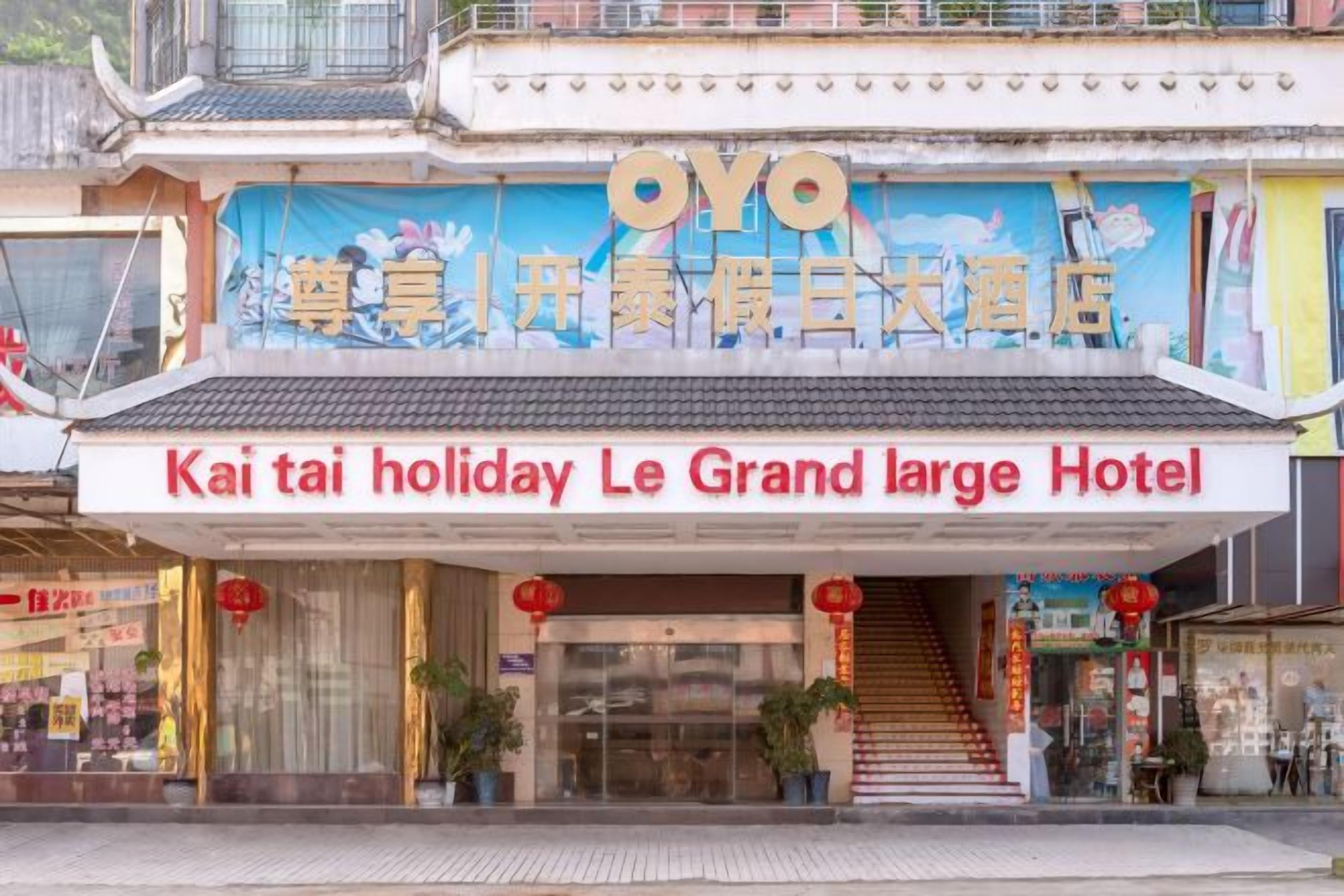 Het uiterlijk van OYO Kai Tai Holiday Le Grand Large Hotel, met een traditionele architectuur, een opvallende ingang en borden in zowel Chinees als Engels.