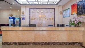 Een hotel receptiebalie met een marmeren aanrecht, een decoratief plafond en een wandklok.