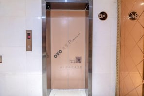 Un ascenseur doté d’un code QR et d’une indication signalant qu’il dessert le 8e étage.