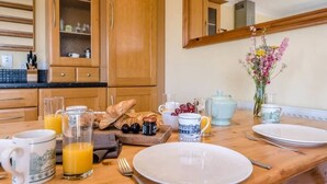 A breakfast setting with a wooden table, plates, cups, and a vase of flowers. - Culver House, Aldeburgh (Aldeburgh)