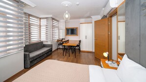 Quarto moderno com sofá, mesa de jantar, lustre e um espelho grande.