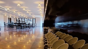 Un'ampia sala con pavimento lucido, file di sedie e un pianoforte.