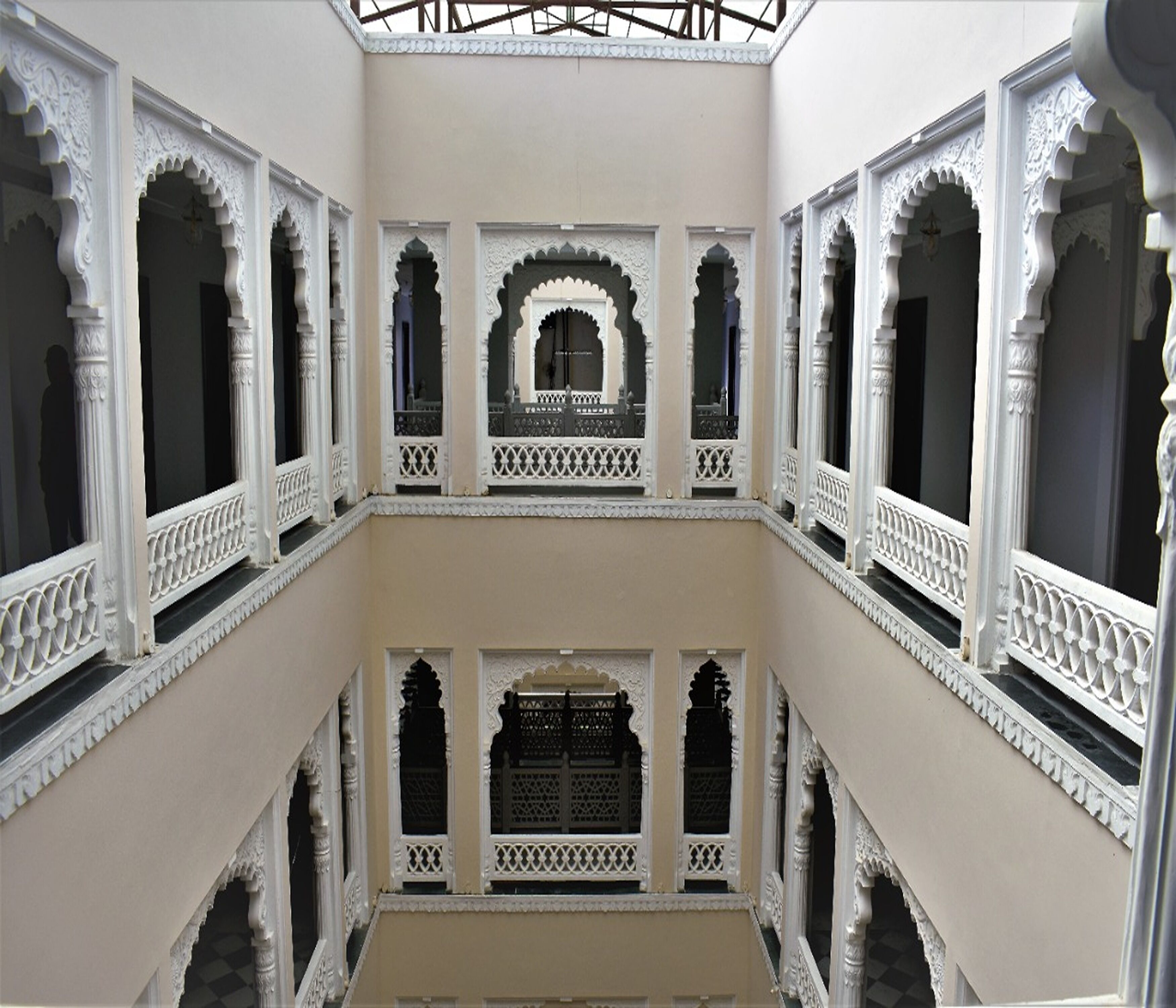 Un interior de varios niveles con arcos blancos ornamentados y balcones.