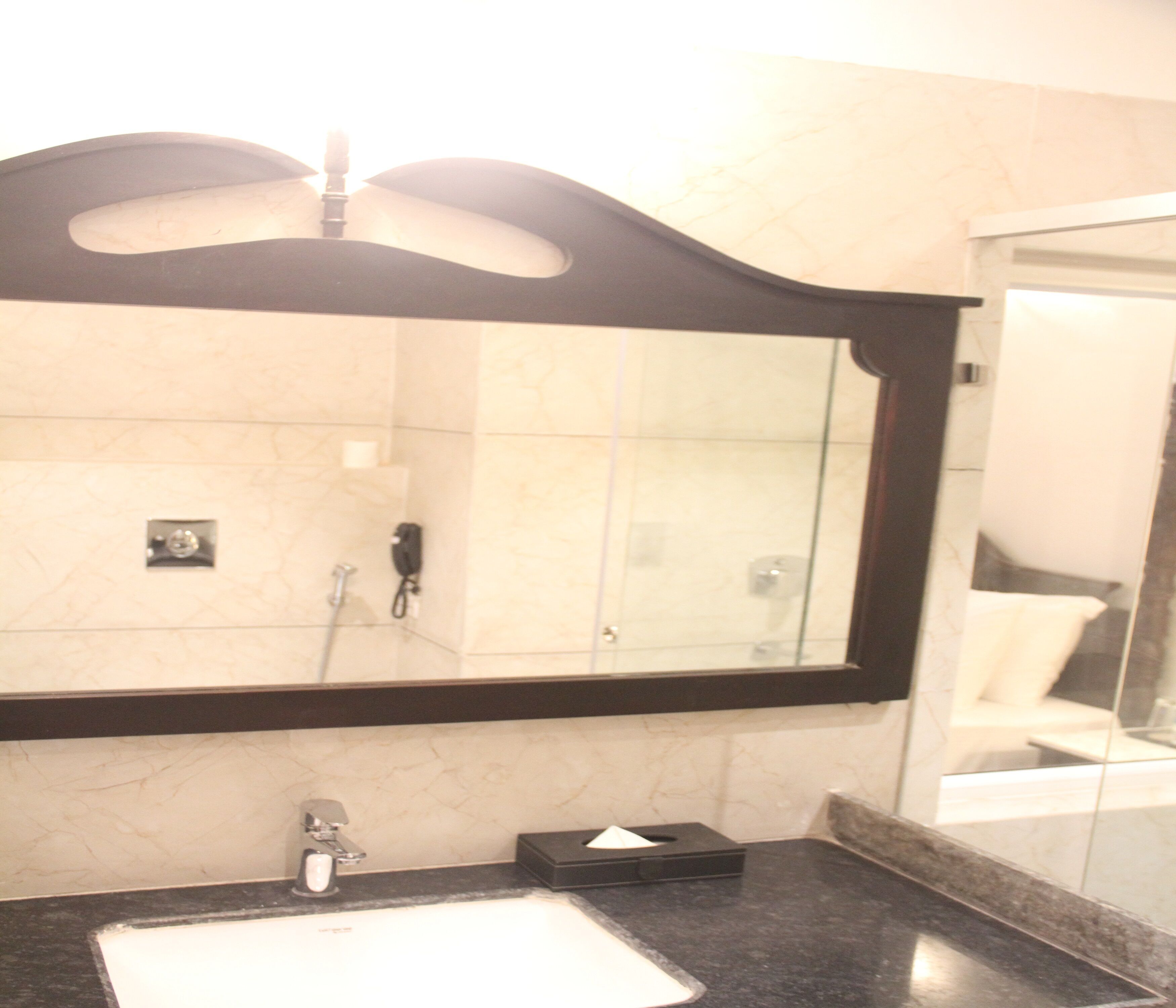 A bathroom with a large mirror, a sink, and a glass shower enclosure.