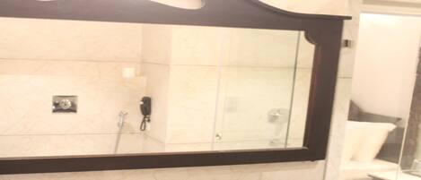 A bathroom with a large mirror, a sink, and a glass shower enclosure.