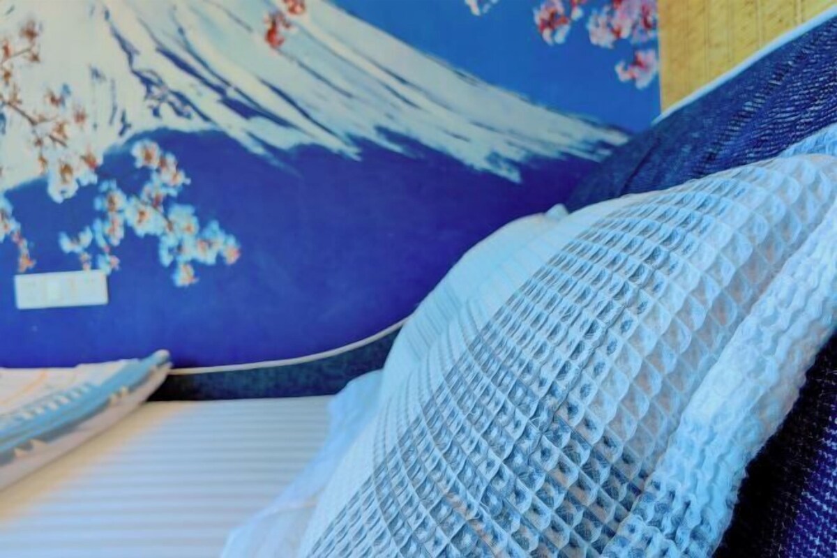Un lit avec un oreiller à motifs bleus et blancs et une couvre-lit à rayures bleues et blanches.