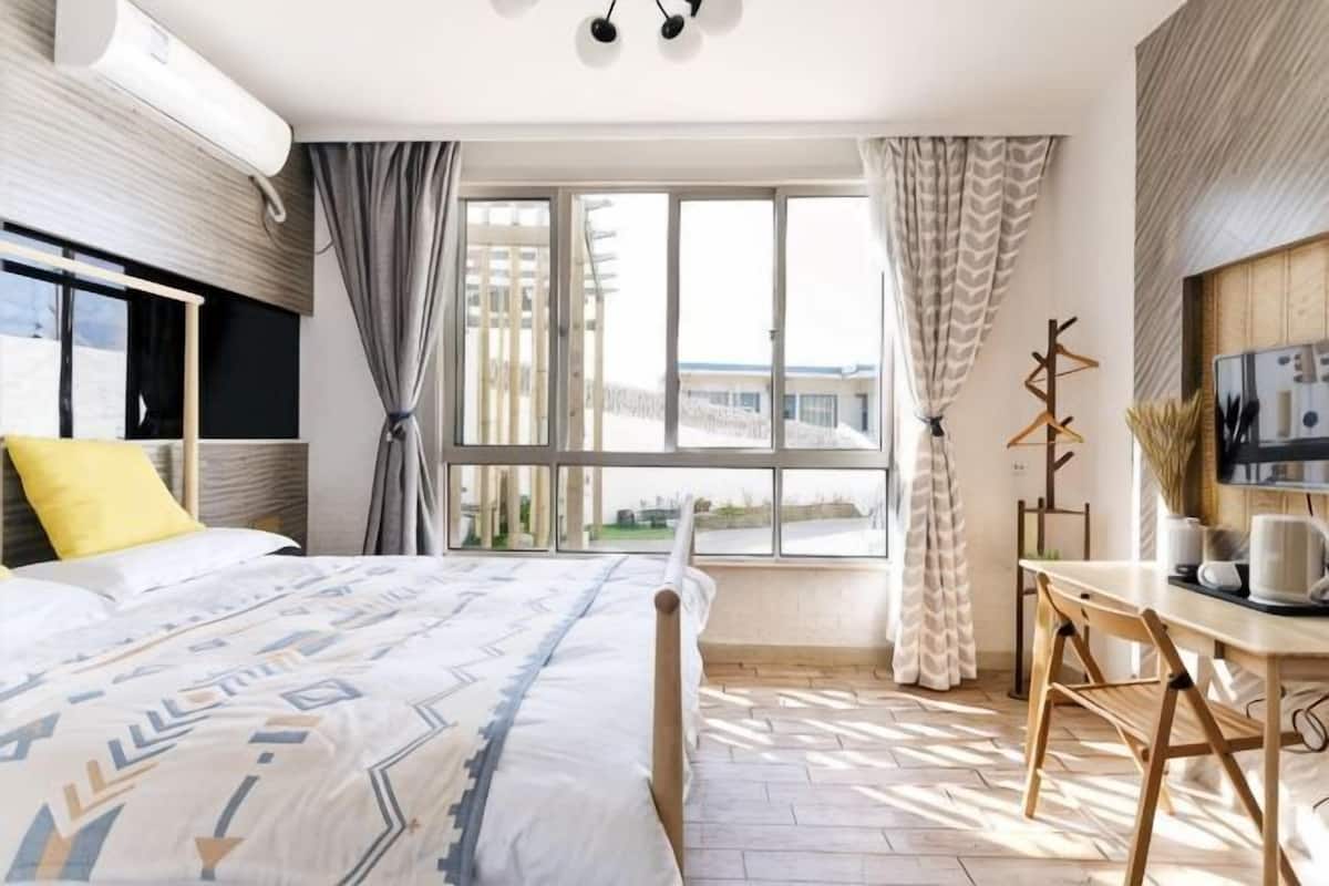 Een slaapkamer met een bed, een bureau en een raam met gordijnen.