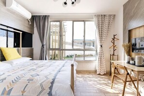 A bedroom with a bed, a desk, and a window with curtains. - Huaniao Island Banshan Banhai Hostel (Shengsi)