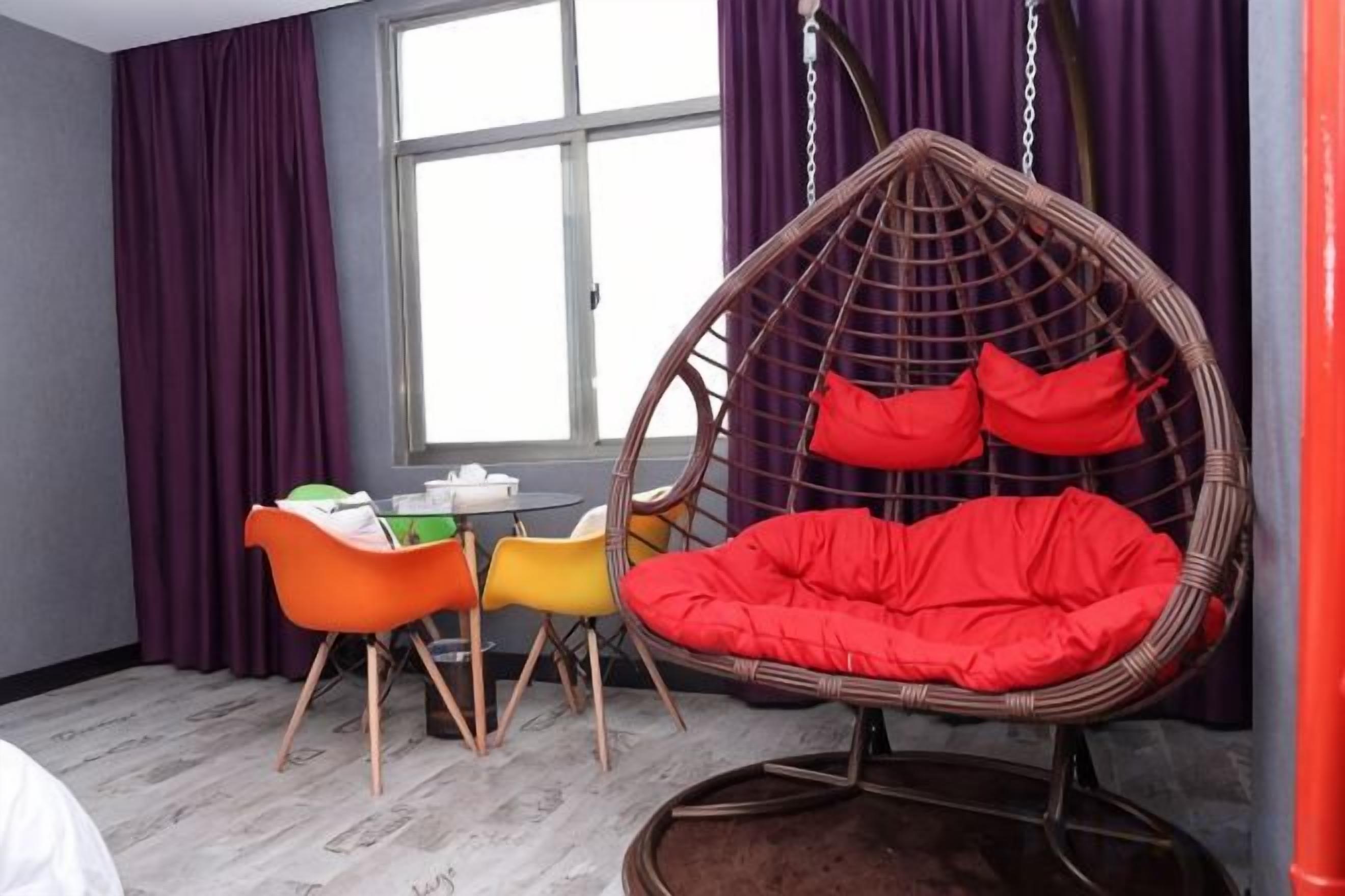 A room with a hanging chair, a table with chairs, and a window with curtains.