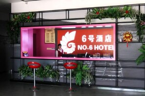 A reception desk with a sign for '6号ホテル NO.6 HOTEL' and a decorative plant arrangement. - Nanri Island No. 6 Hotel (Putian)