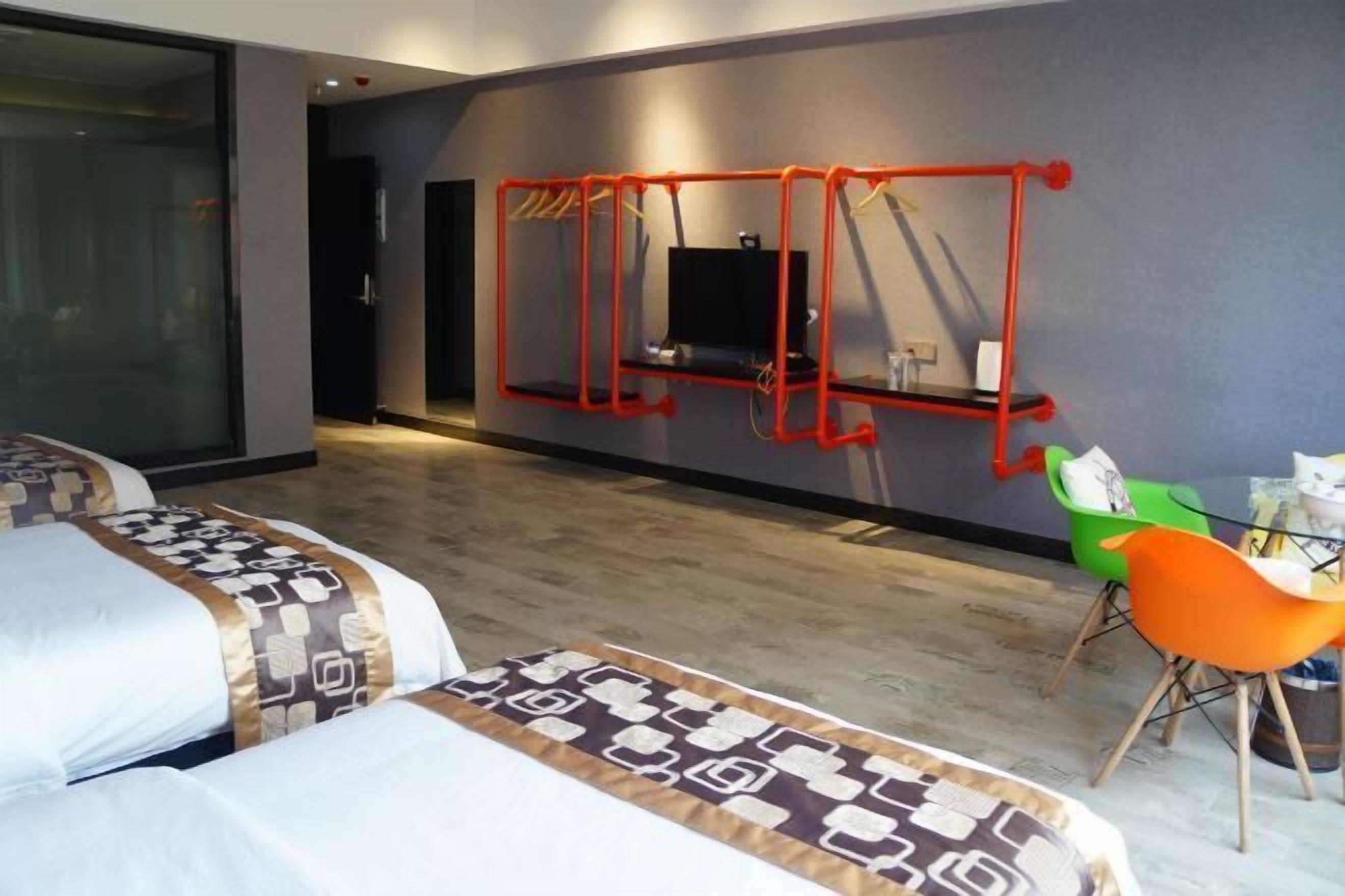 A hotel room with a large bed, a TV mounted on the wall, and a small table with chairs.