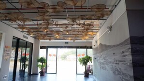 Eine Lobby mit modernem Deckenstil, hängenden Körben, großen Fenstern und Kübelpflanzen.