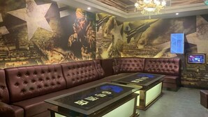 Ein Zimmer mit einer großen Sternwandmalerei, einem gepolsterten Ledersofa und einem Tisch mit einem Bildschirm.