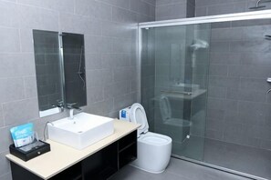 Une salle de bain moderne avec une douche à parois de verre, un lavabo blanc et un miroir.
