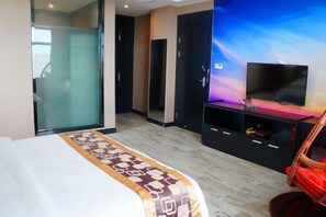 Une chambre d’hôtel avec un lit, une télévision, une armoire et un miroir.