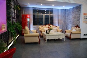 Un hall d’hôtel avec un ensemble de canapés, une table basse et un pilier rouge.