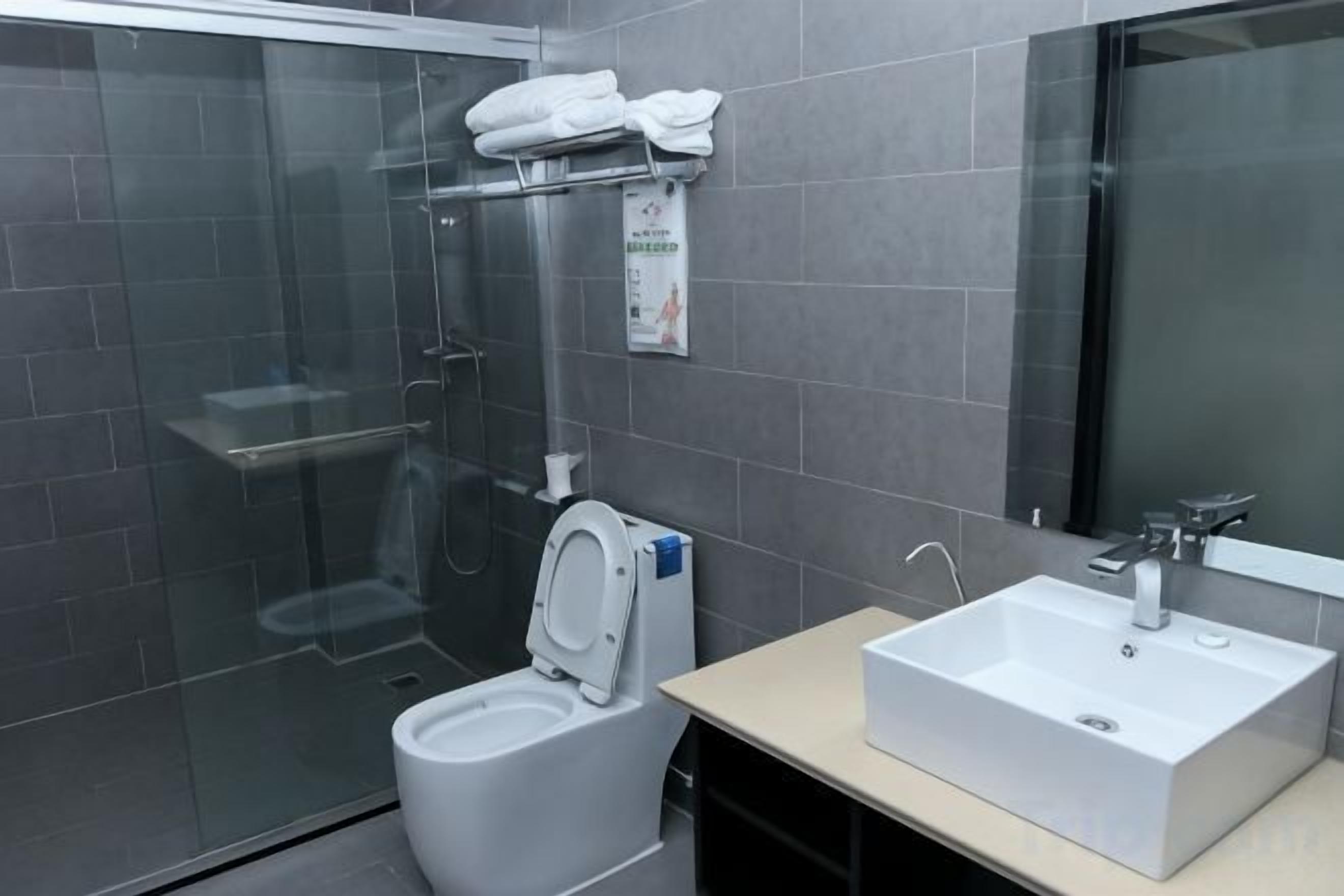 A modern bathroom with a glass-enclosed shower, a white toilet, and a sink with a mirror.