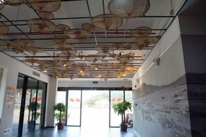 Un hall d’entrée avec un plafond orné de suspensions florales, une fresque murale et des plantes en pot.