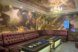 Une salle de cinéma avec un canapé en velours rouge et un grand écran.