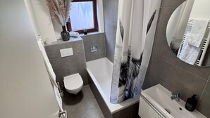 A modern bathroom with a bathtub, toilet, and sink. - Casa Wedel (Lampertheim)