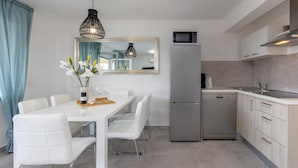 A modern kitchen with a dining area, including a white table, chairs, and a vase with flowers. - Luxurious apartment D (Crikvenica)