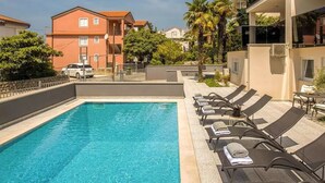 A swimming pool with lounge chairs and a view of surrounding buildings. - Luxurious apartment D (Crikvenica)