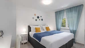 A modern bedroom with a bed, bedside table, lamp, and a wall with circular decorations. - Luxurious apartment D (Crikvenica)