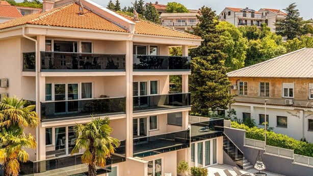 A multi-story hotel with balconies, a swimming pool, and surrounding greenery. - Luxurious apartment D (Crikvenica)