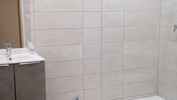 A modern bathroom with a shower, a sink, and a mirror.