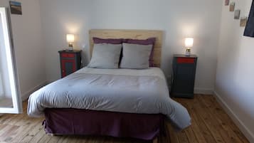 A neatly made bed with a wooden headboard, two bedside tables with lamps, and a wooden floor.