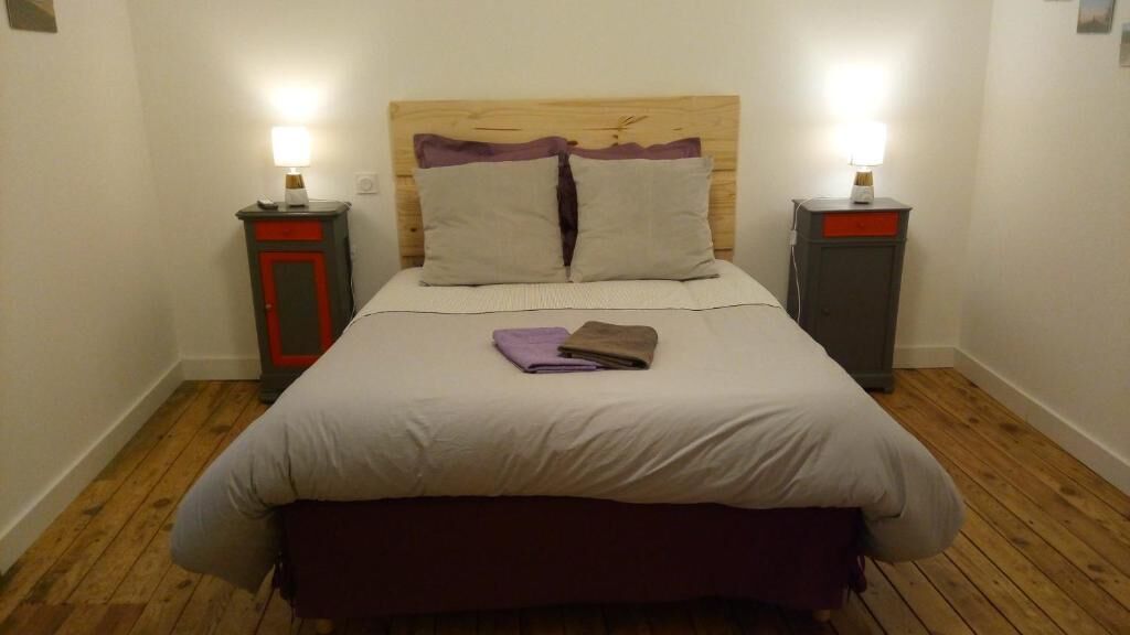 A neatly made bed with a wooden headboard, two bedside tables with lamps, and a wooden floor.