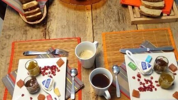 A wooden table with a rustic setting, featuring a variety of foods including apples, bread, and pomegranate seeds.