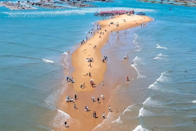 A beach with people and a boat.