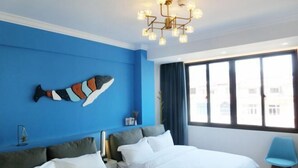 A hotel room with two beds, a blue accent wall, a fish artwork, a modern chandelier, and a view of the city through large windows. - Yumei Inn (Dongshan County)