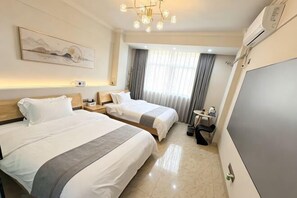 A hotel room with two beds, a desk, a chair, a TV, and a large window with curtains. - Yumei Inn (Dongshan County)