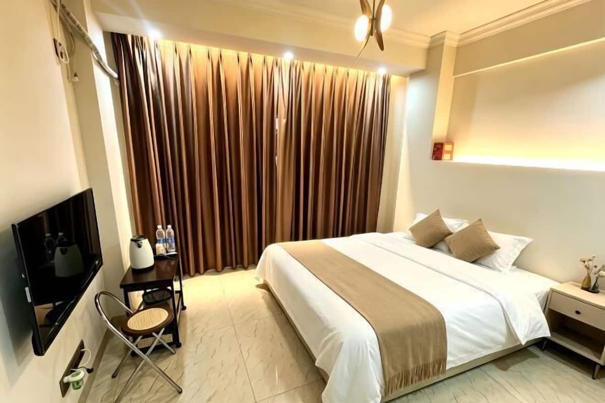 A hotel room with a bed, a TV, a desk, and a chair.