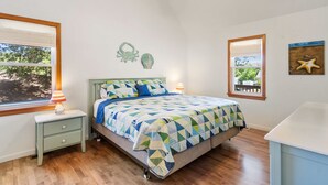 A bedroom with a bed, a nightstand, a ceiling fan, and a window with a view. - Best Kept Secret: Soundside, Hot Tub, Dogs OK (Kill Devil Hills)
