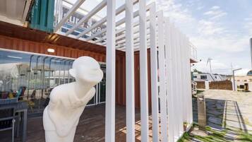 A white sculpture on a wooden deck with a glass enclosure and a white fence structure.