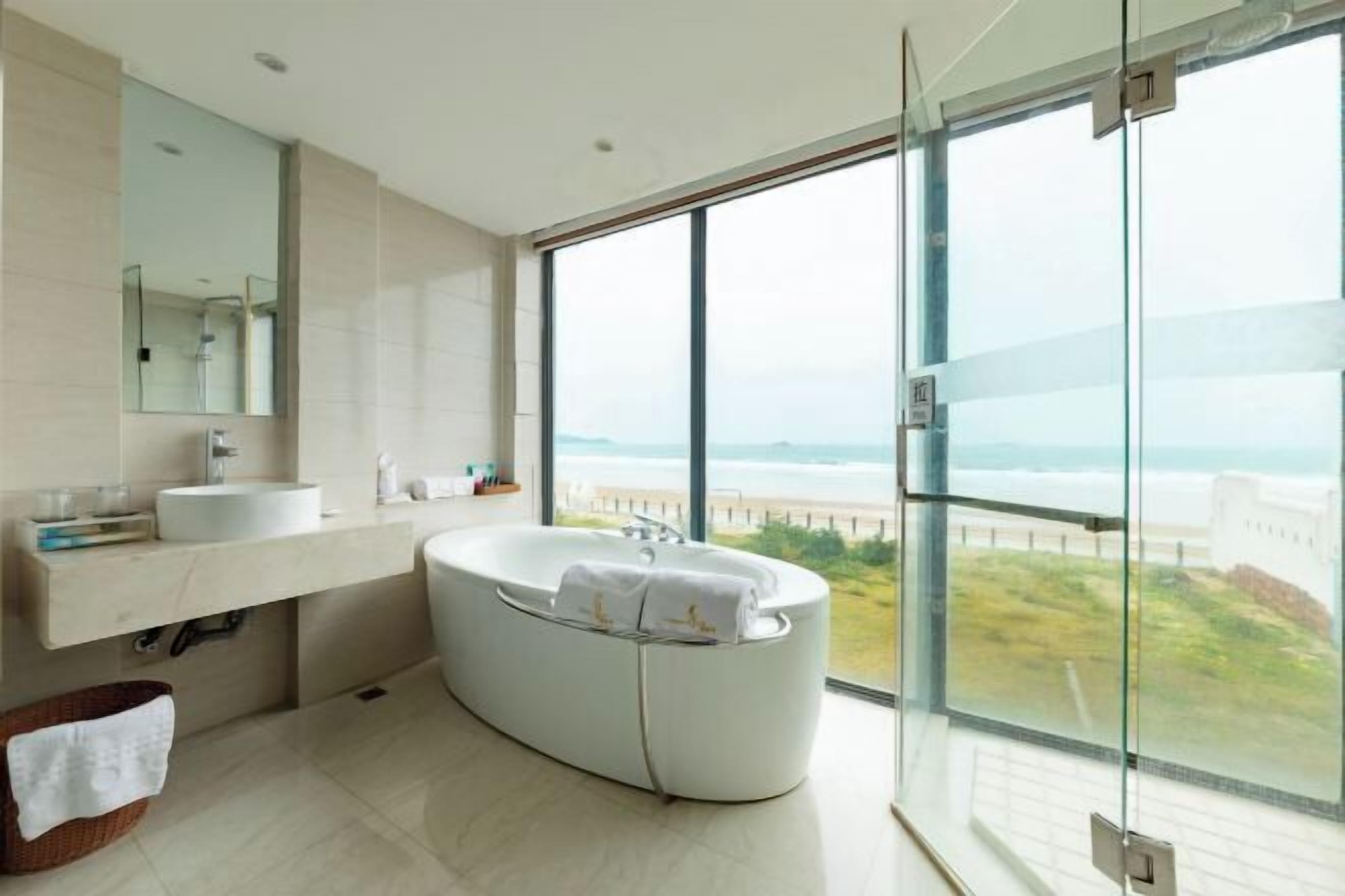A modern bathroom with a large bathtub, a sink, and a mirror.