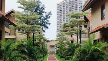 Un sendero bordeado por edificios con una puerta central, rodeado de abundante vegetación y árboles.