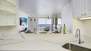 Una cocina con un ventanal grande, un lavamanos de acero inoxidable y vista al océano.