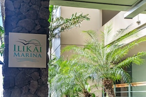 A sign for Ilikai Marina with a stone pillar and palm trees in the background.