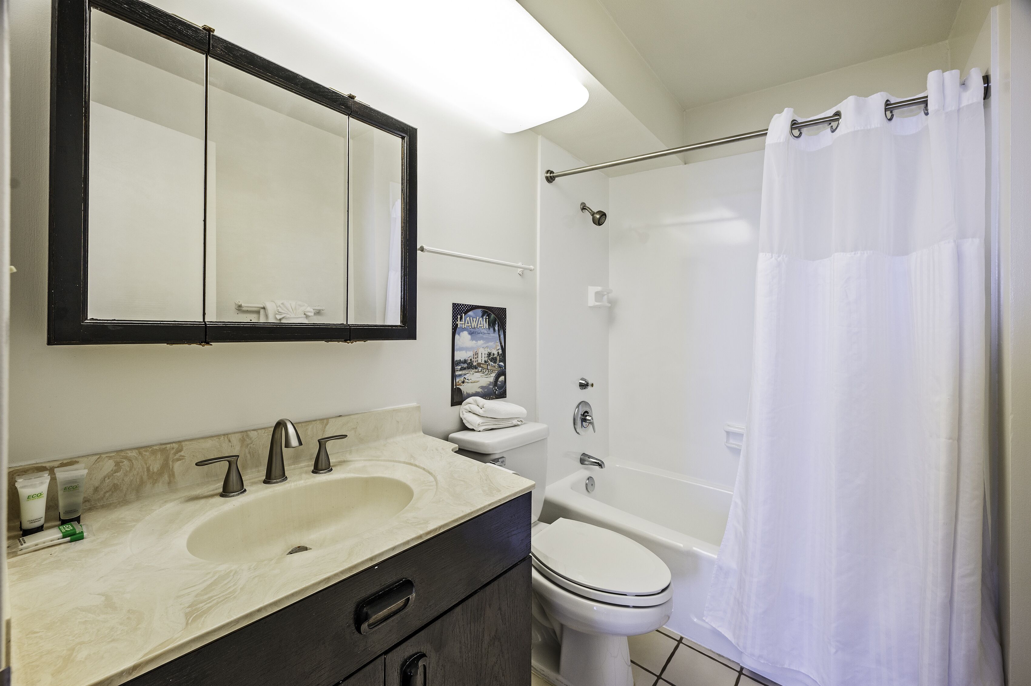 A bathroom with a sink, mirror, toilet, and shower.