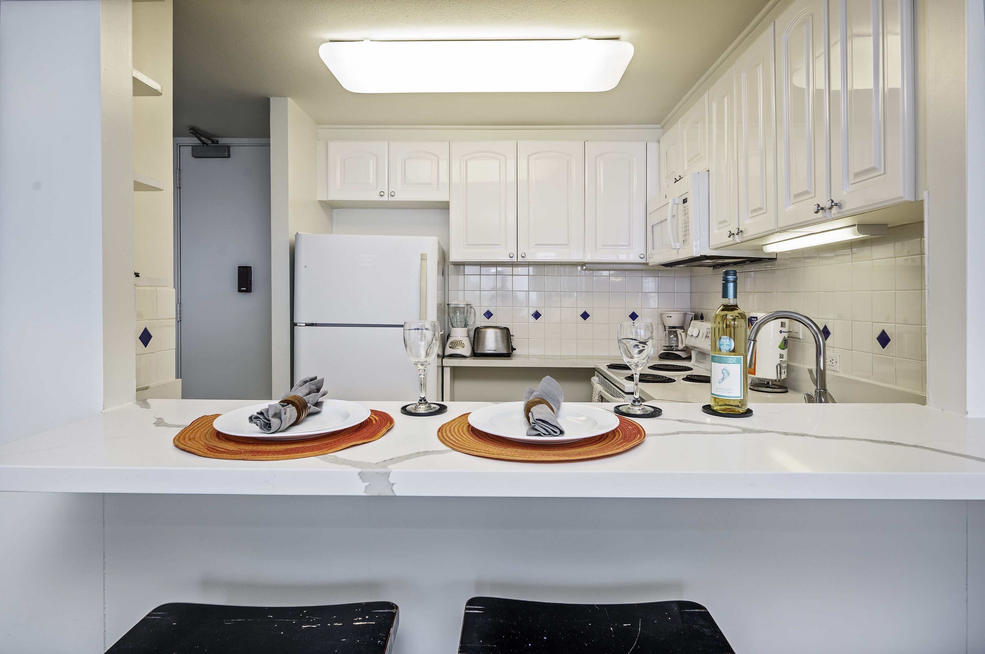 A modern kitchen with white cabinets, a white countertop, and a built-in oven.