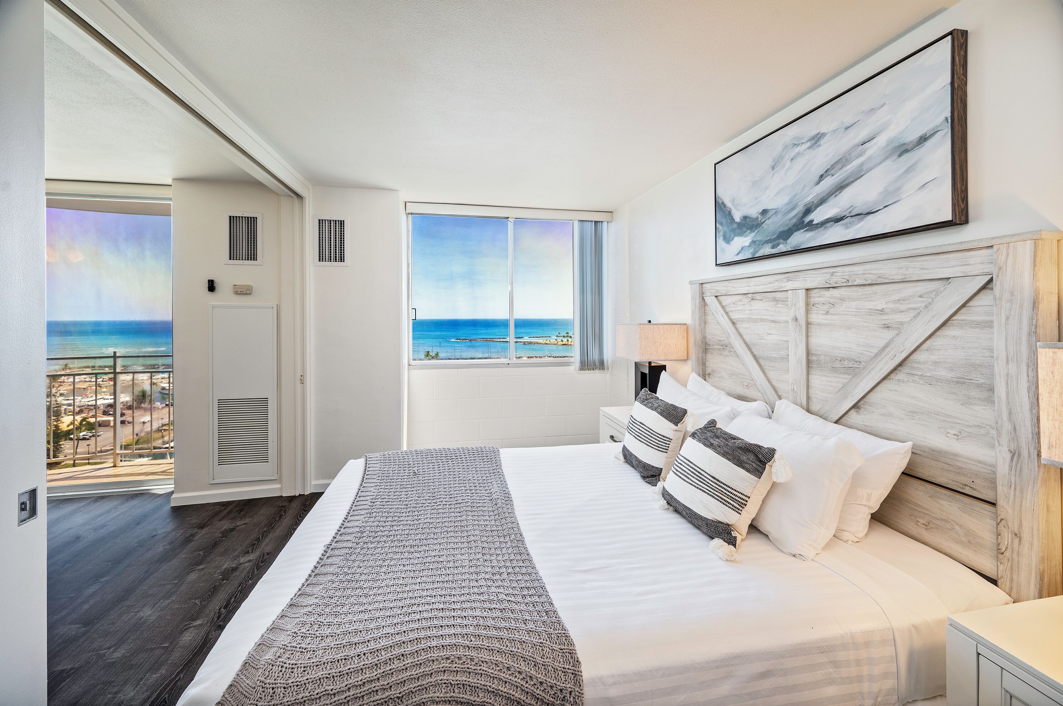 Un dormitorio con una cama grande, vista al océano y cabecera de madera.