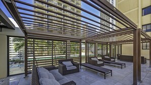 Un área de descanso al aire libre con muebles de mimbre y vista a un edificio de gran altura.