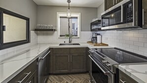 Una cocina moderna con horno empotrado, microondas y electrodomésticos de acero inoxidable.